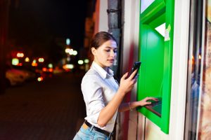Young woman using an ATM at night